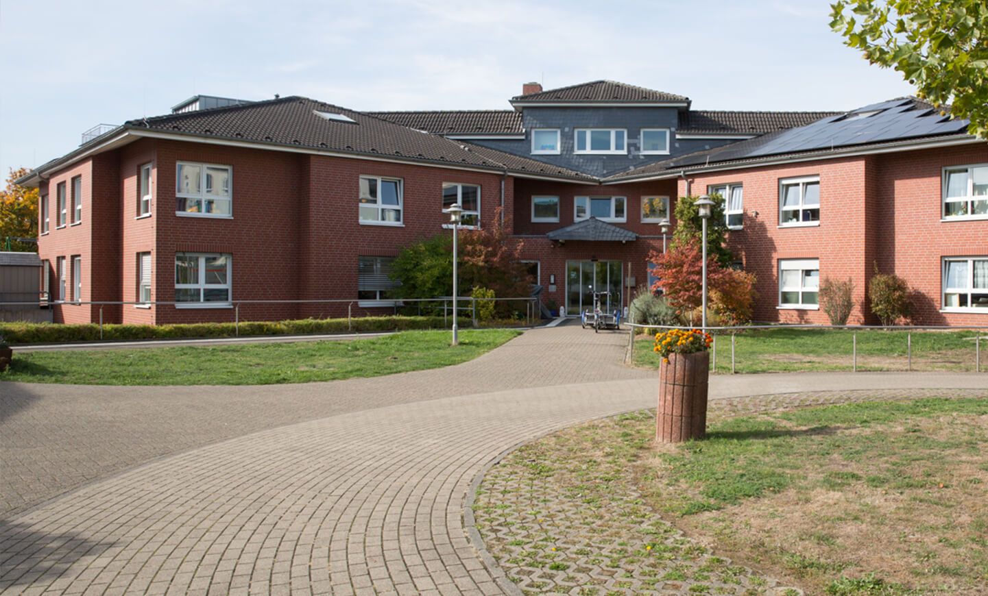 Roter, große Ziegelbau, zweigeschossig mit dunklem Ziegeldach und weißen Fenstern