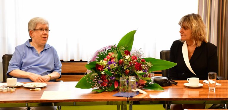 Brigitte Sommer (links), großer bunter Blumenstrauß, Diana Droßel (rechts), alle an einem Tisch.
