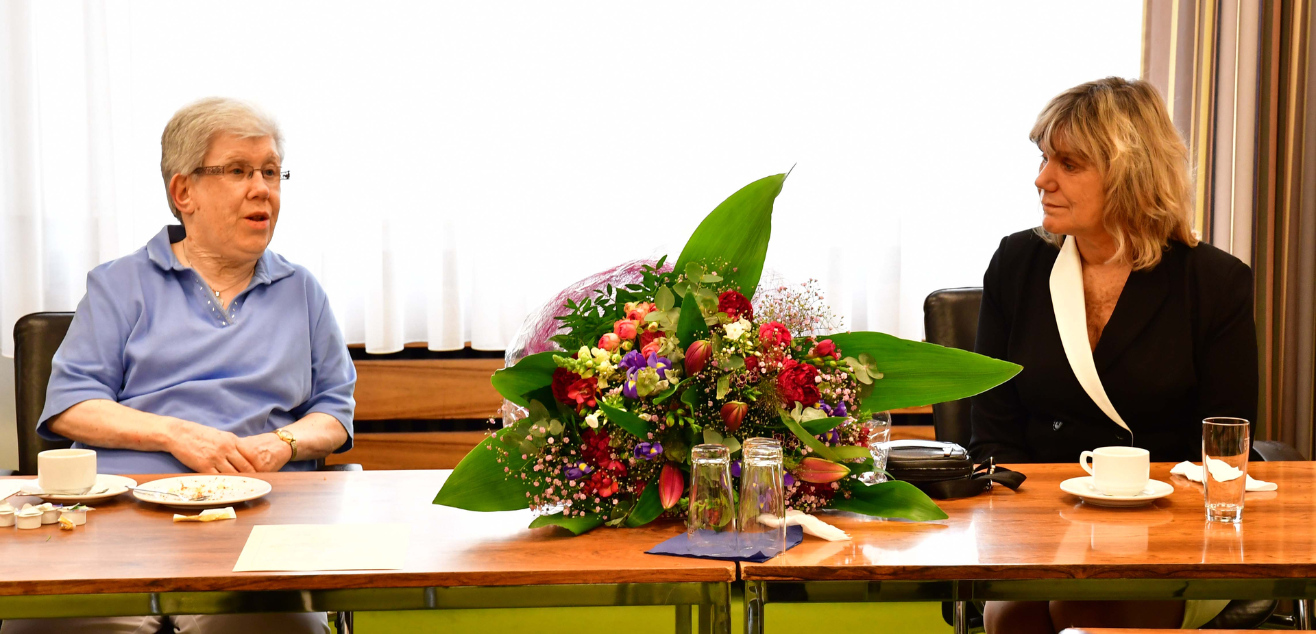 Brigitte Sommer (links), ein Blumenstrauß in der Mitte, Diana Droßel rechts alle an einem Tisch. 